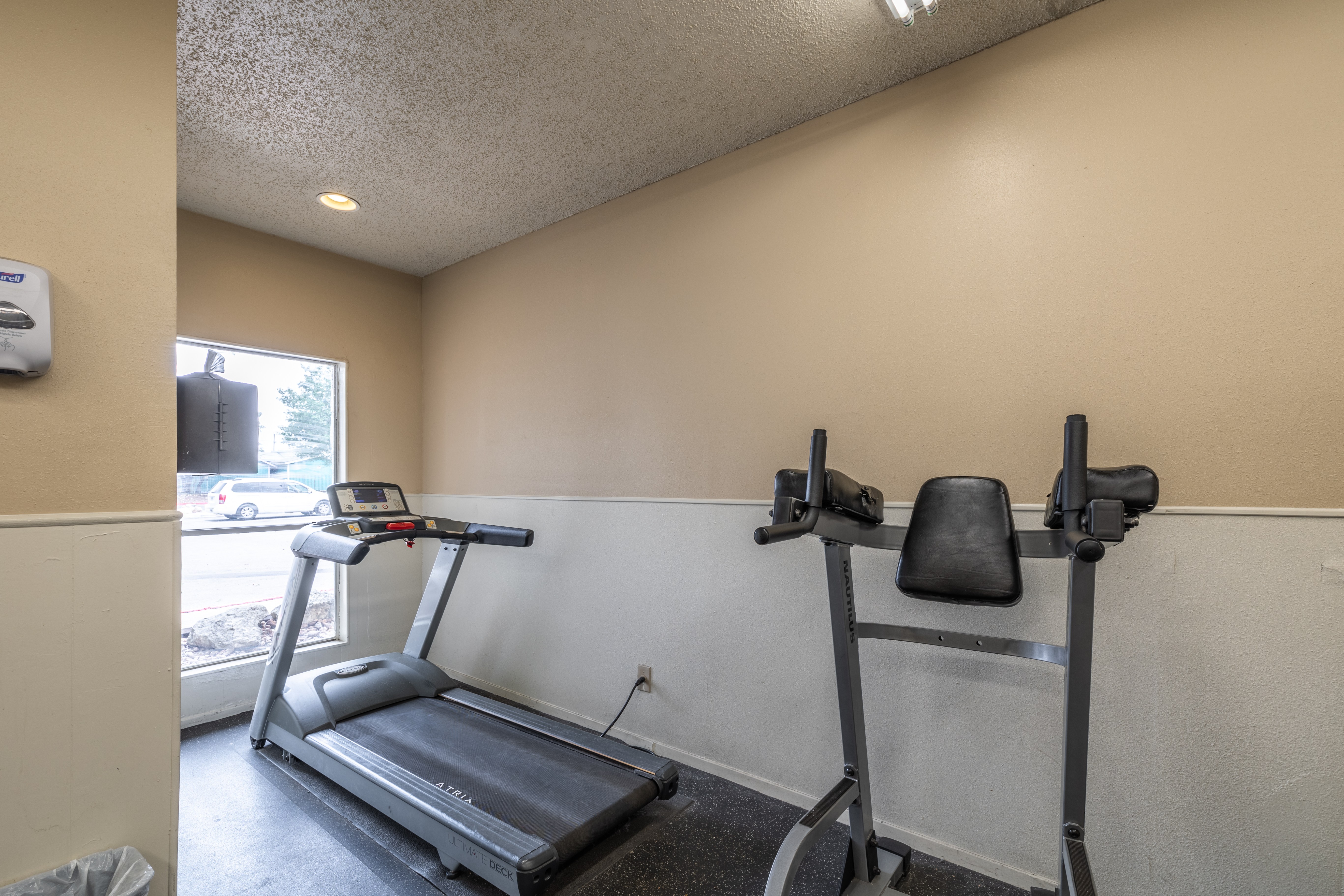 A treadmill and a stationary bike are in a room with a window.